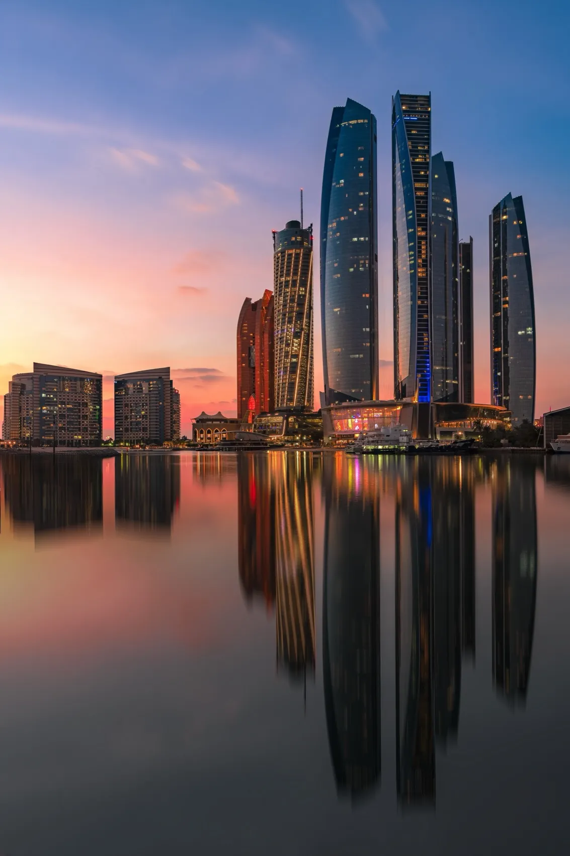 Etihad Towers reflected in still water at dusk, Abu Dhabi